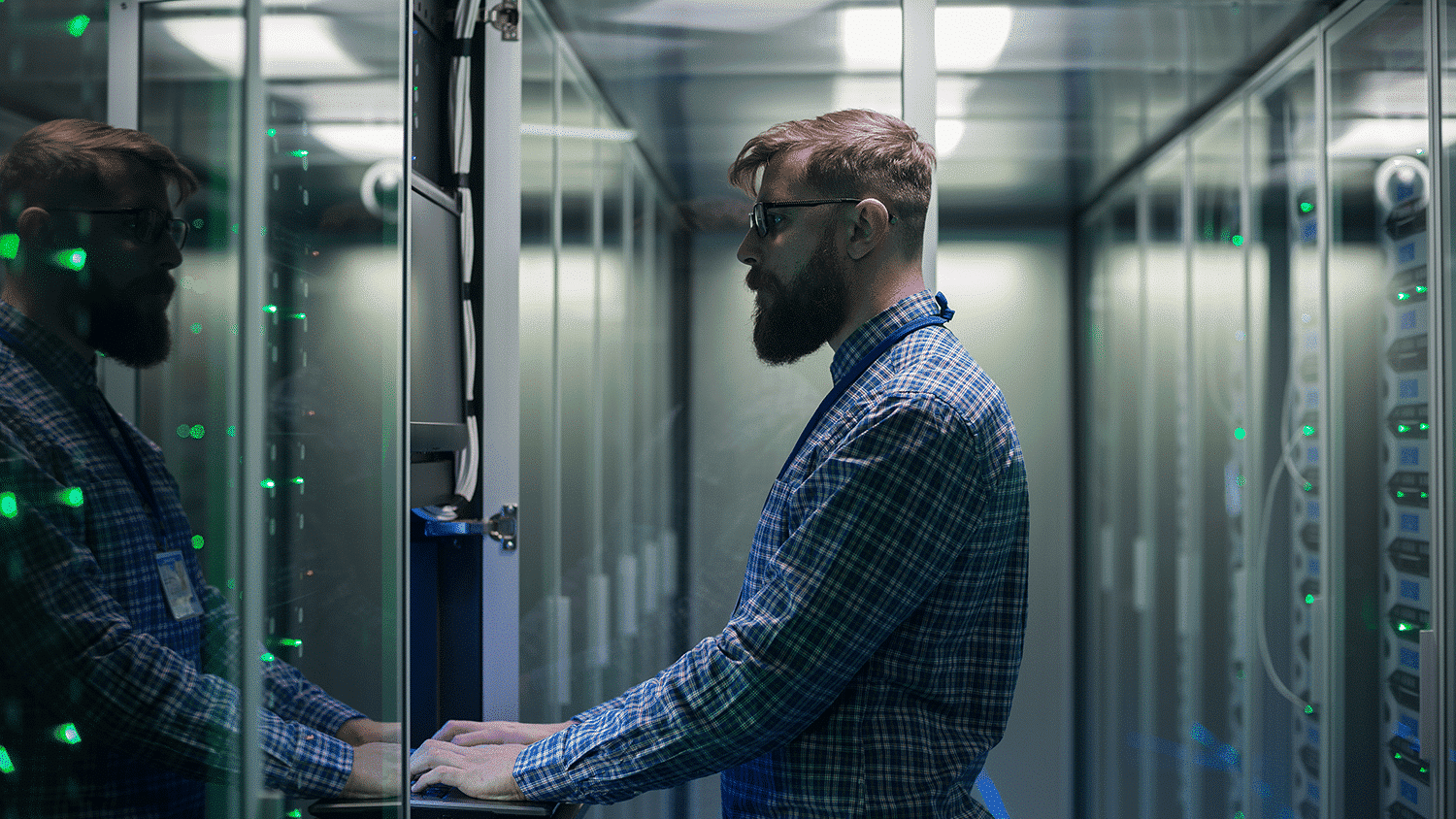 IT engineer in a server room typing into computer