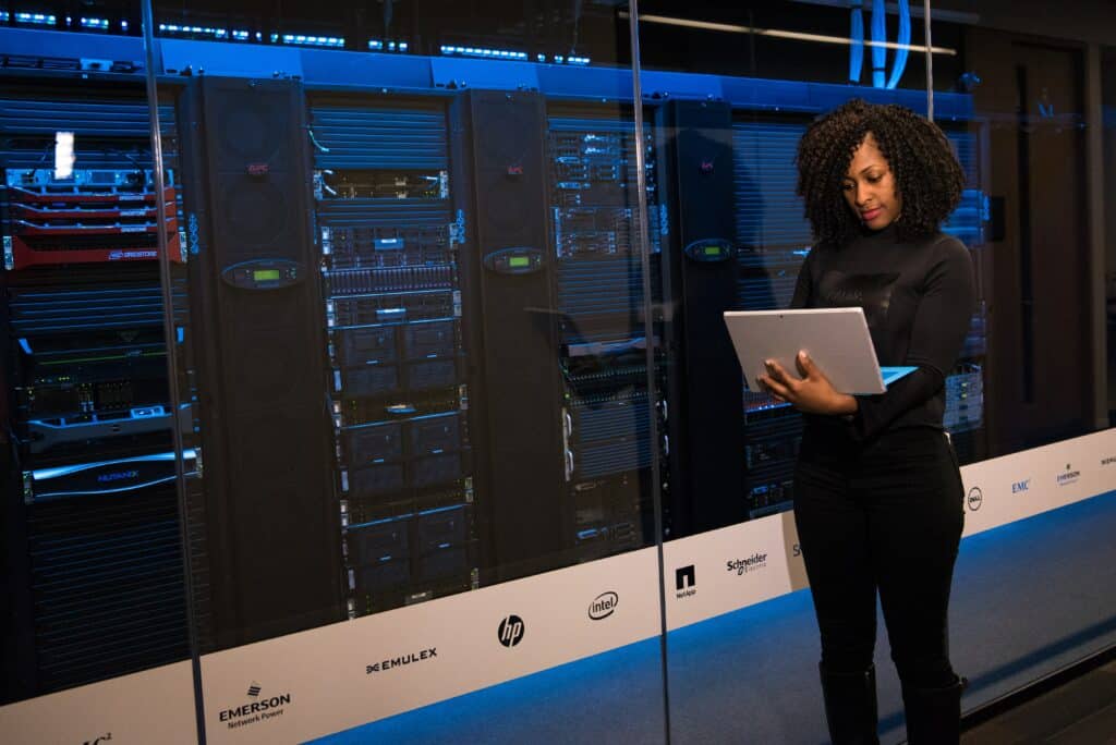 woman works on computer in front of servers - 7 Signs It’s Time to Update Your Network Infrastructure