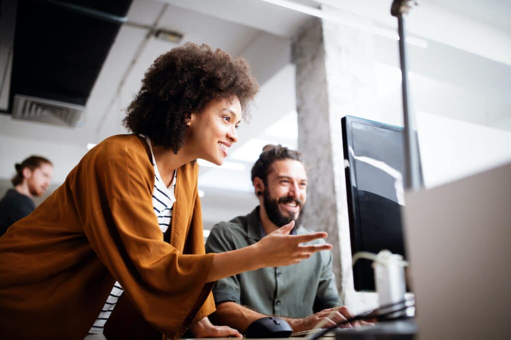 co-managed IT services in Edmonton - woman with afro helps man at computer