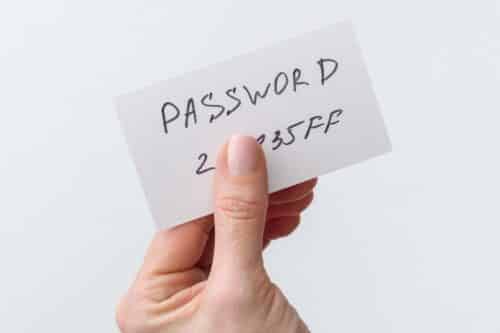 Woman's hand holds a password on paper, that covers the password with finger